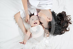 Mother kisses baby lying on the bed closeup