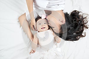 Mother kisses baby lying on the bed closeup