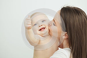 Mother kisses her adorable toddler in cheek, enfant posing photo