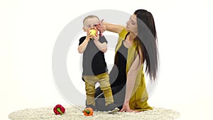 Mother kisses her baby, he laughs. White background. Slow motion