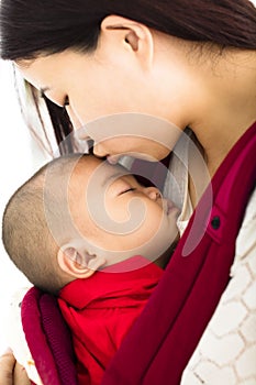 Mother kissing baby in baby carrier