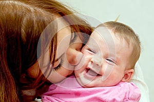 Mother kissing baby, kid laughing.