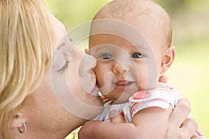 Mother kissing baby outdoors