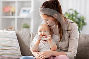 mother kissing baby with teething toy at home