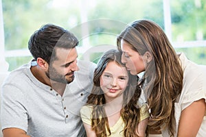 Mother kissing daughter while father watching them