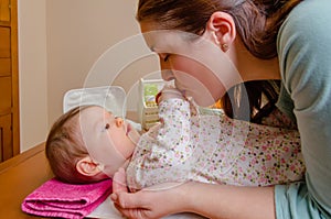 Mother kissing hands of her baby lying