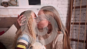 Mother kissing happy little daughter`s cheek