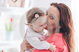 Mother kissing her baby daughter.