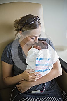 Mother kissing her newborn premature baby in the hospital