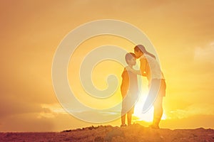 Mother kissing his son in a forehead on the sunset summer day