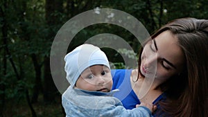 Mother kissing and smiling with her little son in the forest - slow motion.