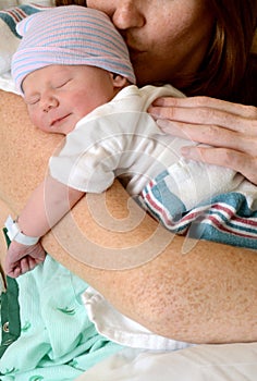 Mother kissing smiling newborn baby
