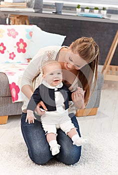 Mother kneeling on floor with baby girl on lap