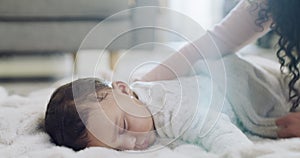 Mother laying her baby to sleep with love, care and kisses in the living room of their family home. Cute, adorable and