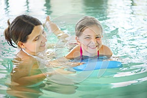 Mother learning to swim her little daughter in an indoor swimmin