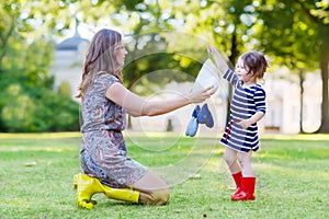 Mother and little adorable child in yellow and red rubber boots