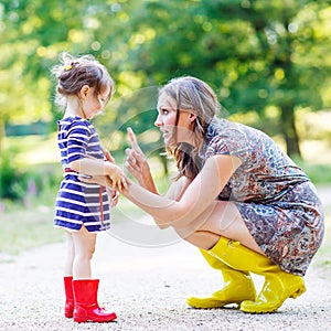 Mother and little adorable child in yellow rubber boots