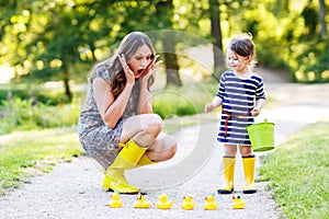 Mother and little adorable child in yellow rubber boots