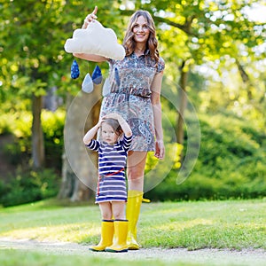 Mother and little adorable child in yellow rubber boots