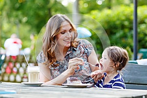 Mother and little adorable kid girl drinking coffee in outdoor c