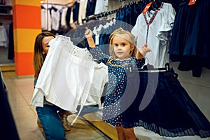 Mother and little baby choosing skirt, kid`s store