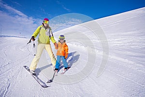 Mother and little boy learning to ski holding hand