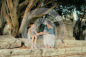 Mother with little boy in the park under a tree