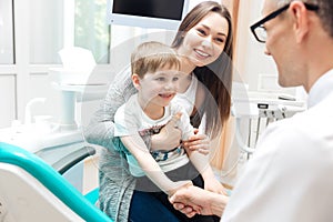 Mother and little boy talking to dentist in dental clinic