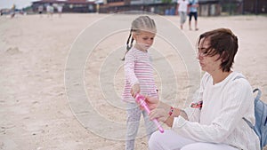 Mother With Little Child Blowing Soap Bubbles On Sea Beach Traveling with one Children Family Summer Vacation