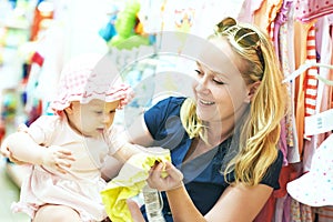 Mother with little child choosing baby apparel in shop