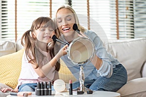 Mother and little Daughter applying cosmetic with brushes