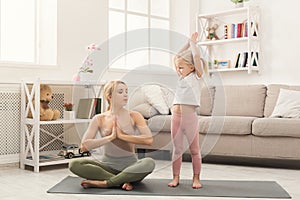 Mother and little daughter doing yoga together