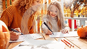 Mother and little daughter drawing spooky ghost for halloween