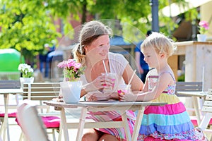 Mother and little daughter drinking in cafe
