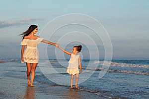 Mother and little daughter are having fun on the beach