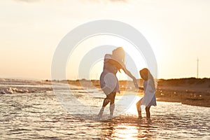 Mother and little daughter are having fun on the beach