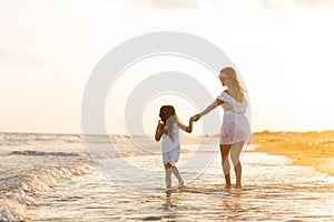 Mother and little daughter are having fun on the beach