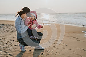 Mother and little daughter having fun on the beach. Authentic lifestyle image