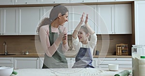 Mother and little daughter having fun while prepare dough