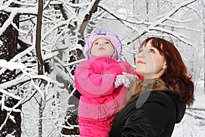 Mother with little daughter look up in woods