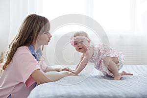 Mother and little daughter in play in the bedroom on the bed