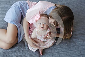 Mother and little daughter in play in the bedroom on the bed