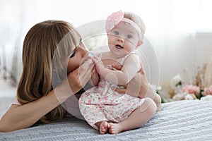 Mother and little daughter in play in the bedroom on the bed