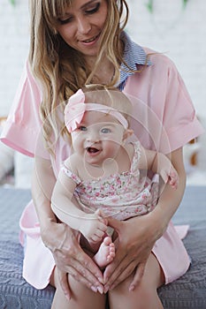 Mother and little daughter in play in the bedroom on the bed