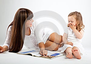 Mother and little daughter reading book