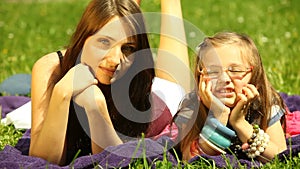 Mother with little daughter relaxing on the meadow.