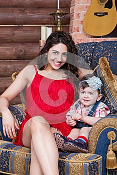 Mother with little daughter sitting on armchair in