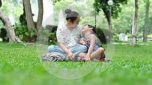 Mother and little daughter sitting on the grass together in the park.