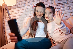 Mother and daughter speaking with father on phone at night at home.