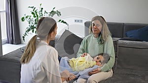 Mother with little daughter talking to health visitor at home